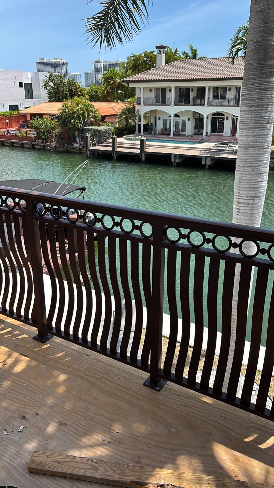 The finished balcony railing framing the canal and a waterfront home across the water