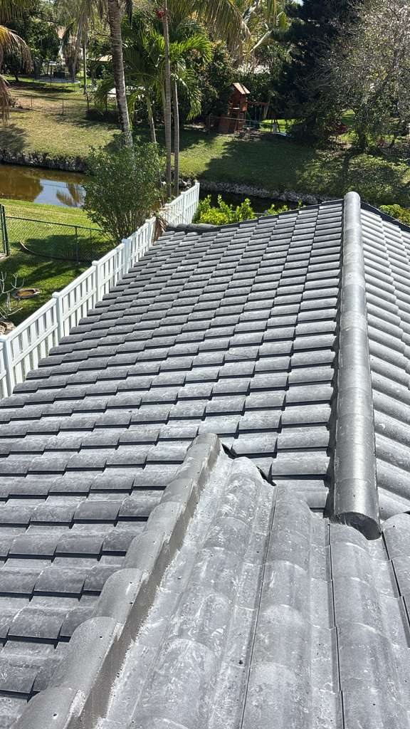 Gray tile roof completed by MTC overlooking a backyard lake and palm trees in South Florida